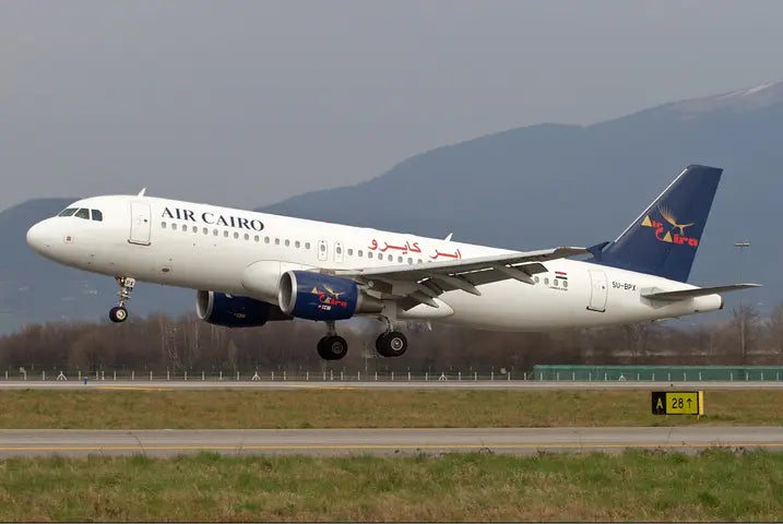 Air Cairo Airbus A320 aircraft landing on a runway with mountains in the background, showing the airline's logo and markings.