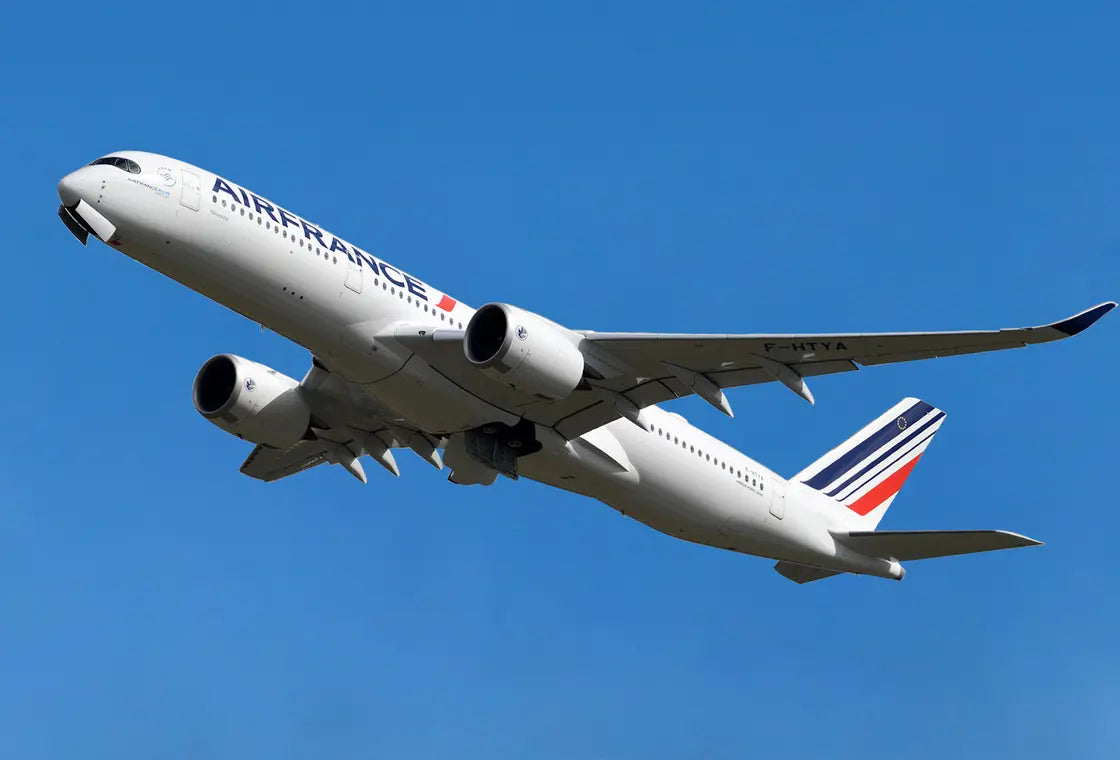 Air France Airbus A350 aircraft with registration F-HTYA soaring against a clear blue sky, showcasing its sleek design and engine detail.