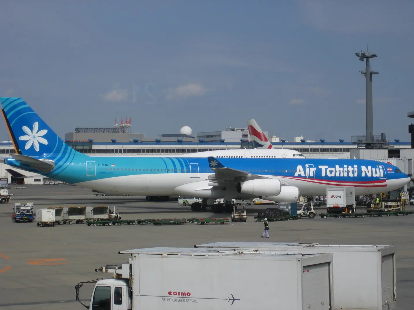 Air Tahiti Nui Airbus A340-313 (F-OLOV) parked at Narita International Airport with service vehicles and equipment surrounding it.