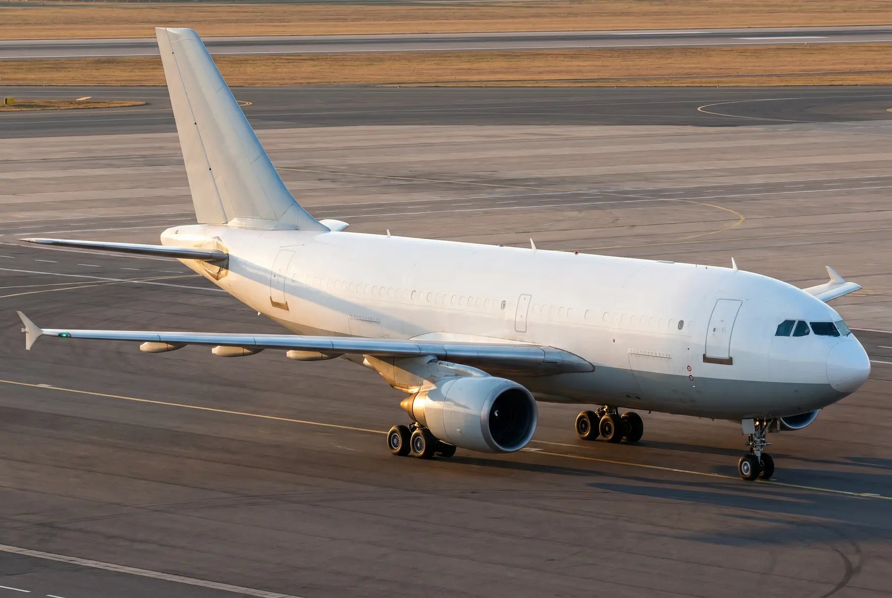 Airbus A310-300F cargo aircraft on the tarmac, viewed from the side at an airport during the daytime.