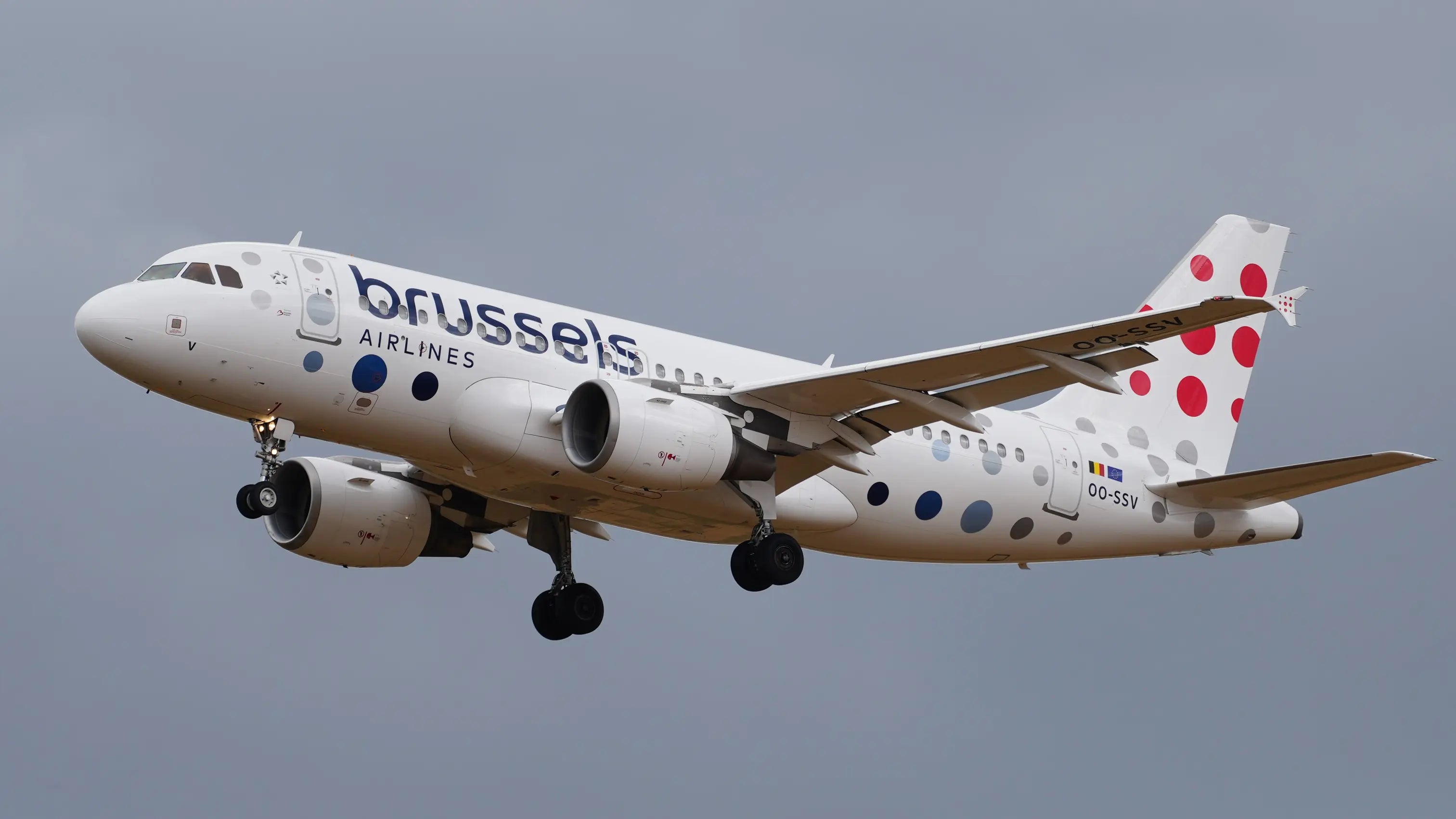 Brussels Airlines Airbus A319-111 OO-SSV aircraft approaching for landing against a cloudy sky, featuring red polka dots on the tail and fuselage.