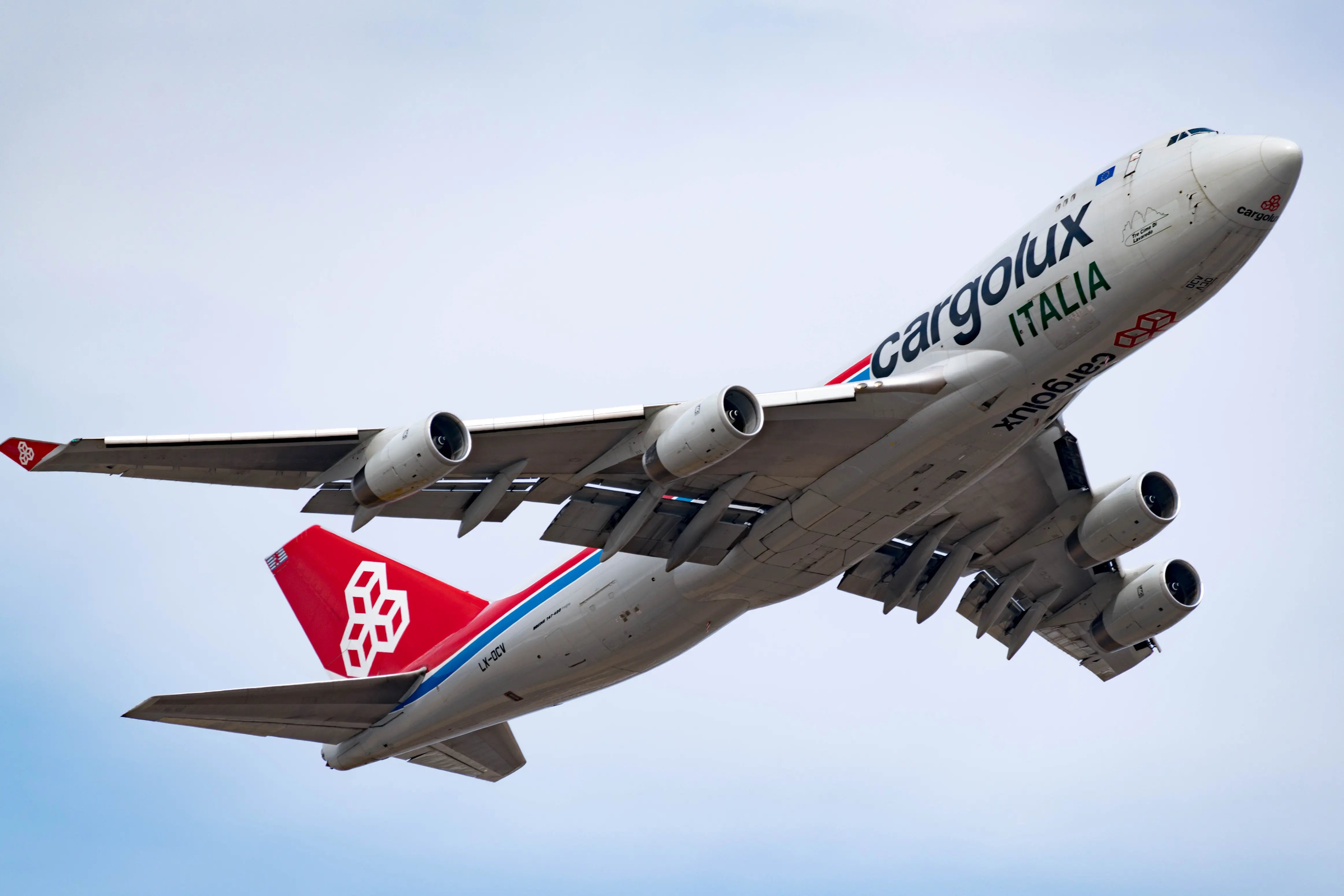 Cargolux Italia Boeing 747 aircraft taking off, viewed from below against a clear sky.