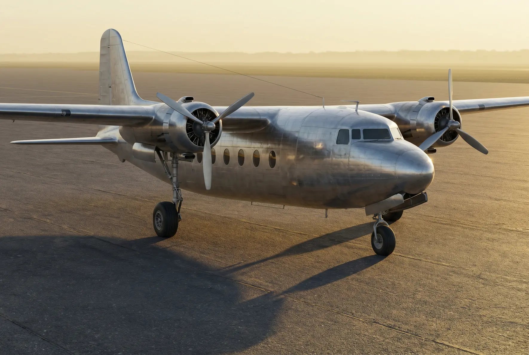 Side view of a vintage Douglas DC-5 aircraft on a runway, featuring its twin engines and propellers, under a clear sky with a warm sunset glow.