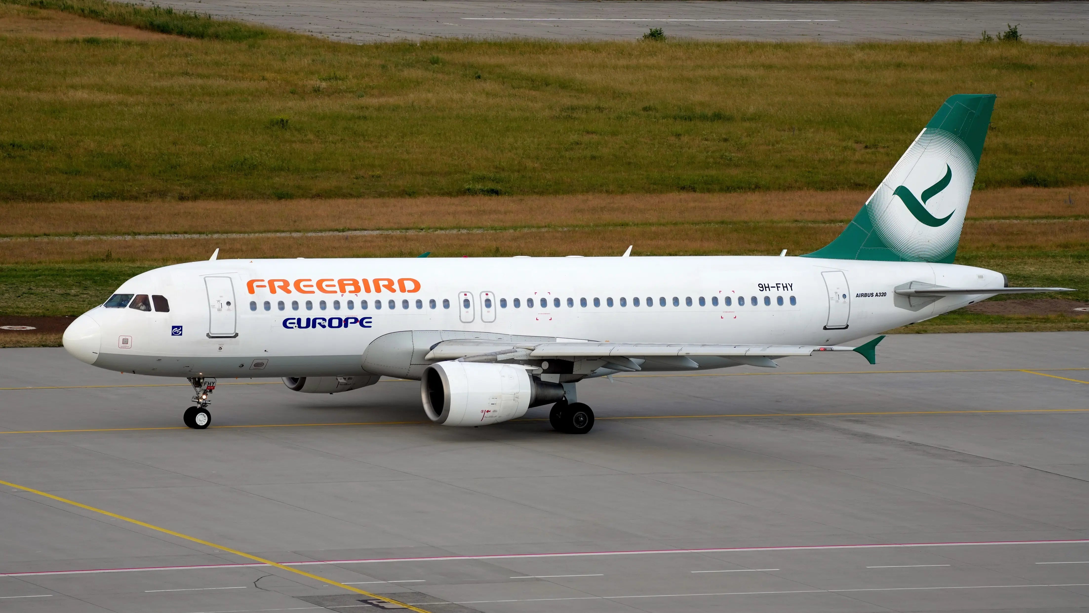 Freebird Airlines Europe Airbus A320-214 on the tarmac at Leipzig Halle Airport, featuring a green tail fin with a distinctive logo.