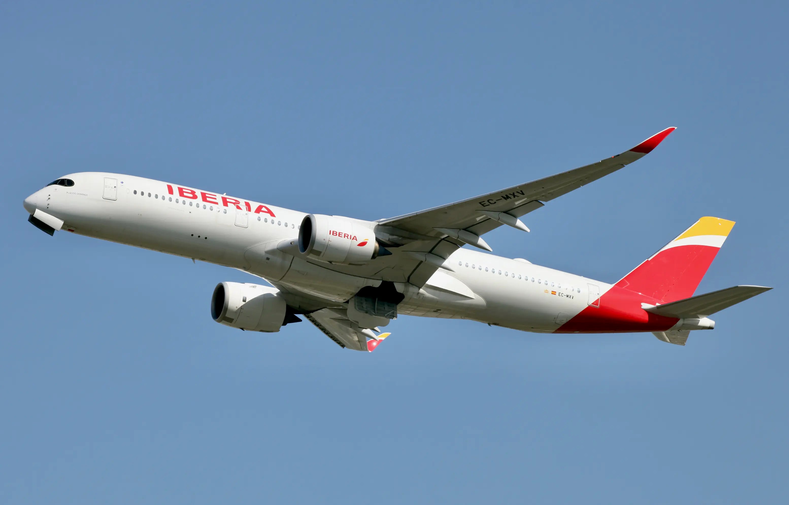 Iberia Airbus A350-900 aircraft, registration EC-MXV, in flight with clear blue sky background.