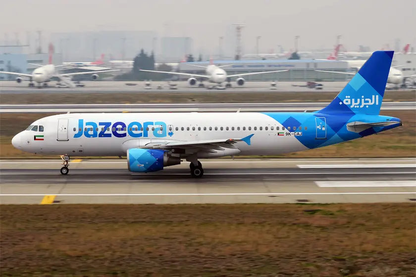Jazeera Airways Airbus A320-214, registration 9K-CAJ, taxiing on the runway at an airport, with other aircraft visible in the background.