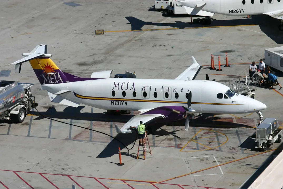 Mesa Airlines Beechcraft Be.1900 aircraft parked at an airport gate, with N131YV registration, being serviced by ground crew and refueled.
