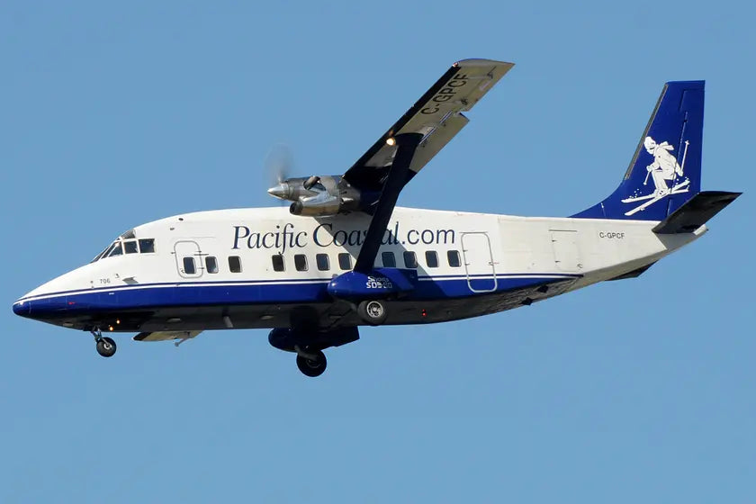 Pacific Coastal Airlines Short 360-300 aircraft in flight, marked with C-GPCF, showcasing a skiing figure on the tail, against a clear blue sky.