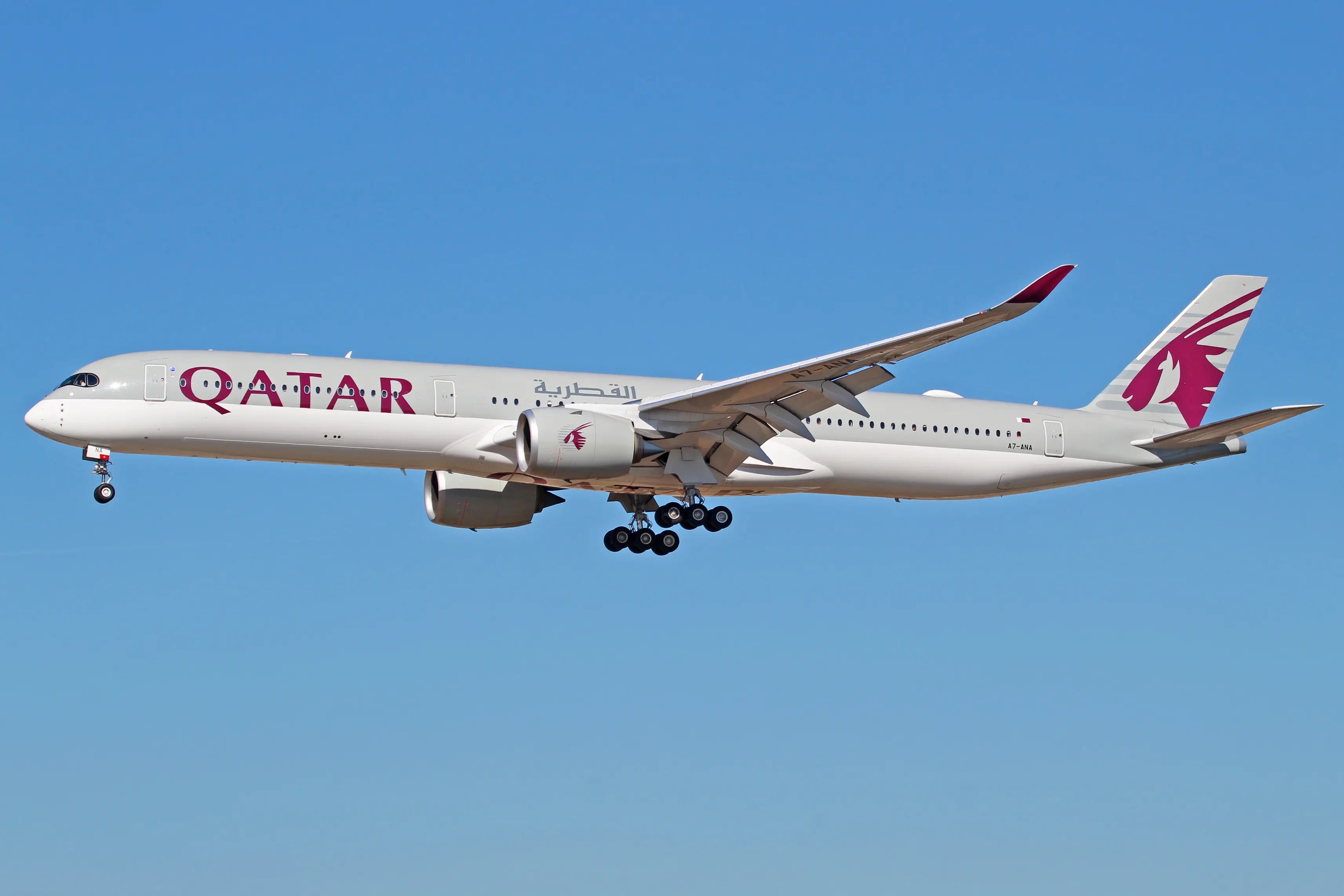 Qatar Airways Airbus A350-1000 airplane in flight, side view against a clear blue sky, showing its fuselage, engines, and landing gear.