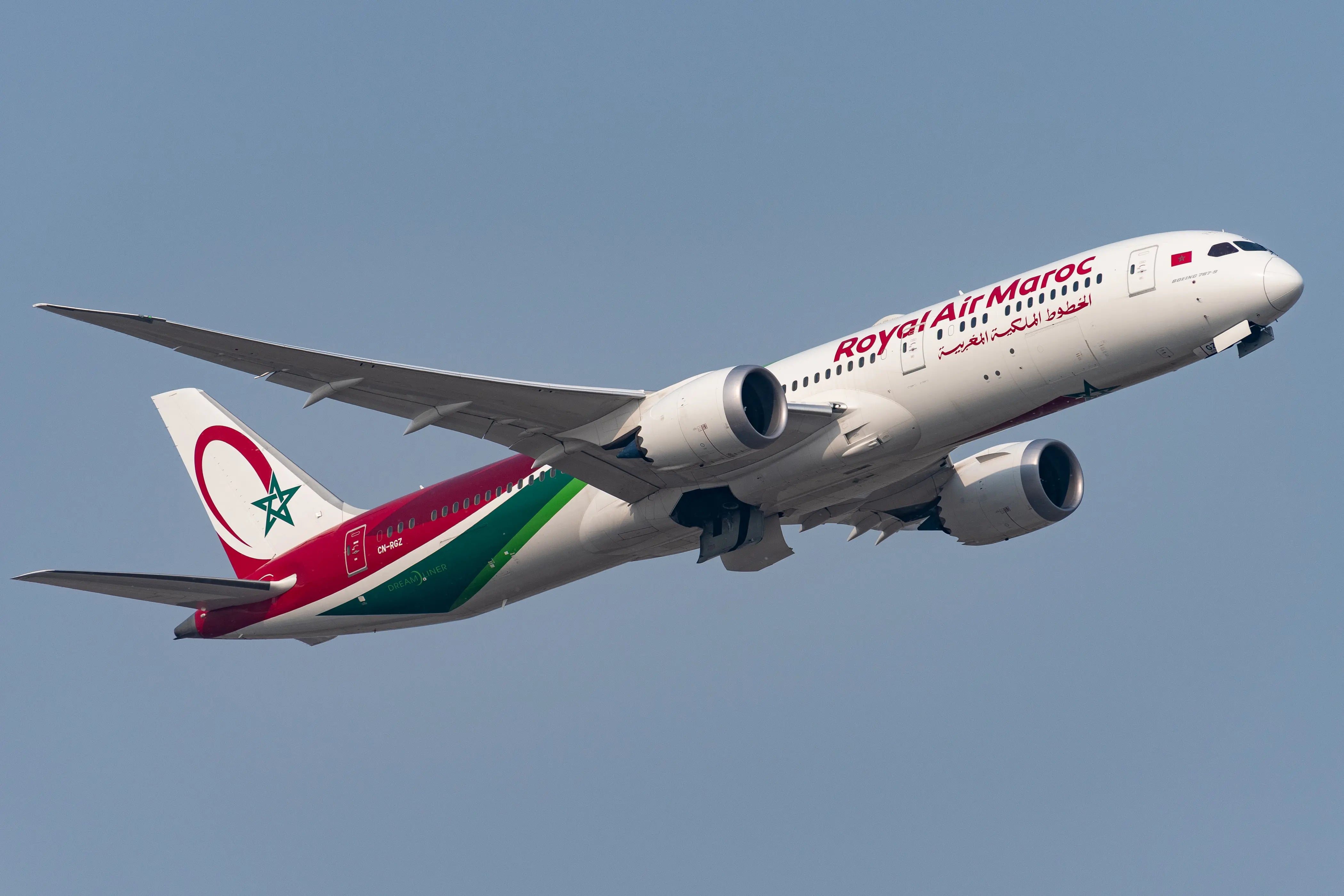 A Royal Air Maroc airplane ascending against a clear blue sky, showing the airline's red, green, and white color scheme and logo on its tail.
