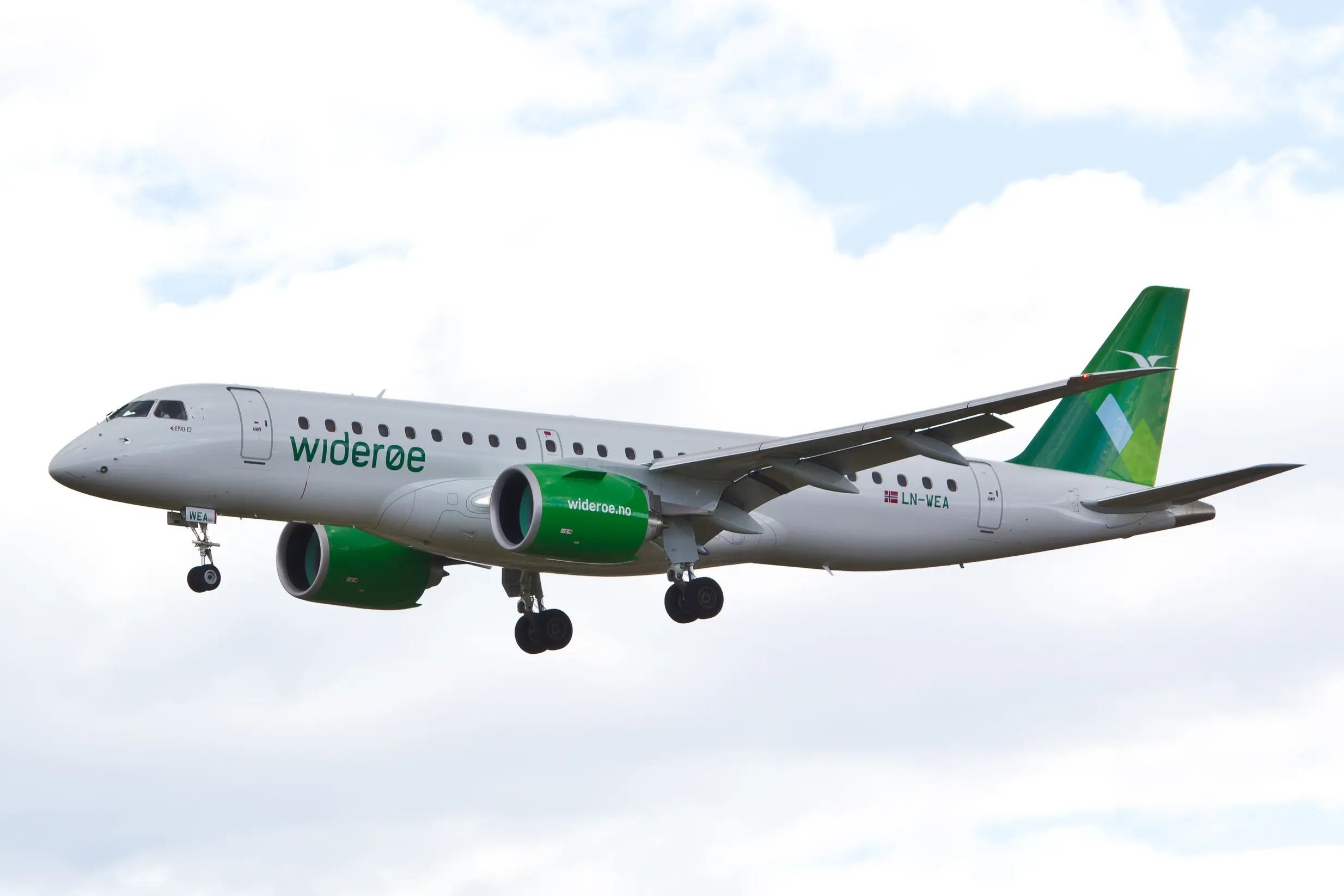 Widerøe Embraer E190-E2 aircraft, registration LN-WEA, in flight against a cloudy sky, featuring green and white livery and visible landing gear.