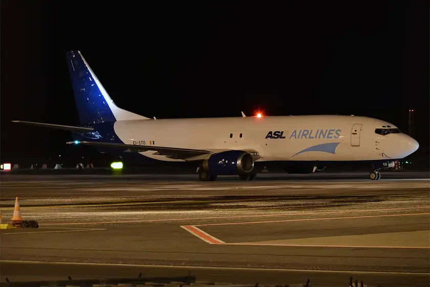 Boeing 737-43Q SF from ASL Airlines Ireland, registration EI-STO, parked on an airport tarmac at night with lights on the tail and fuselage.