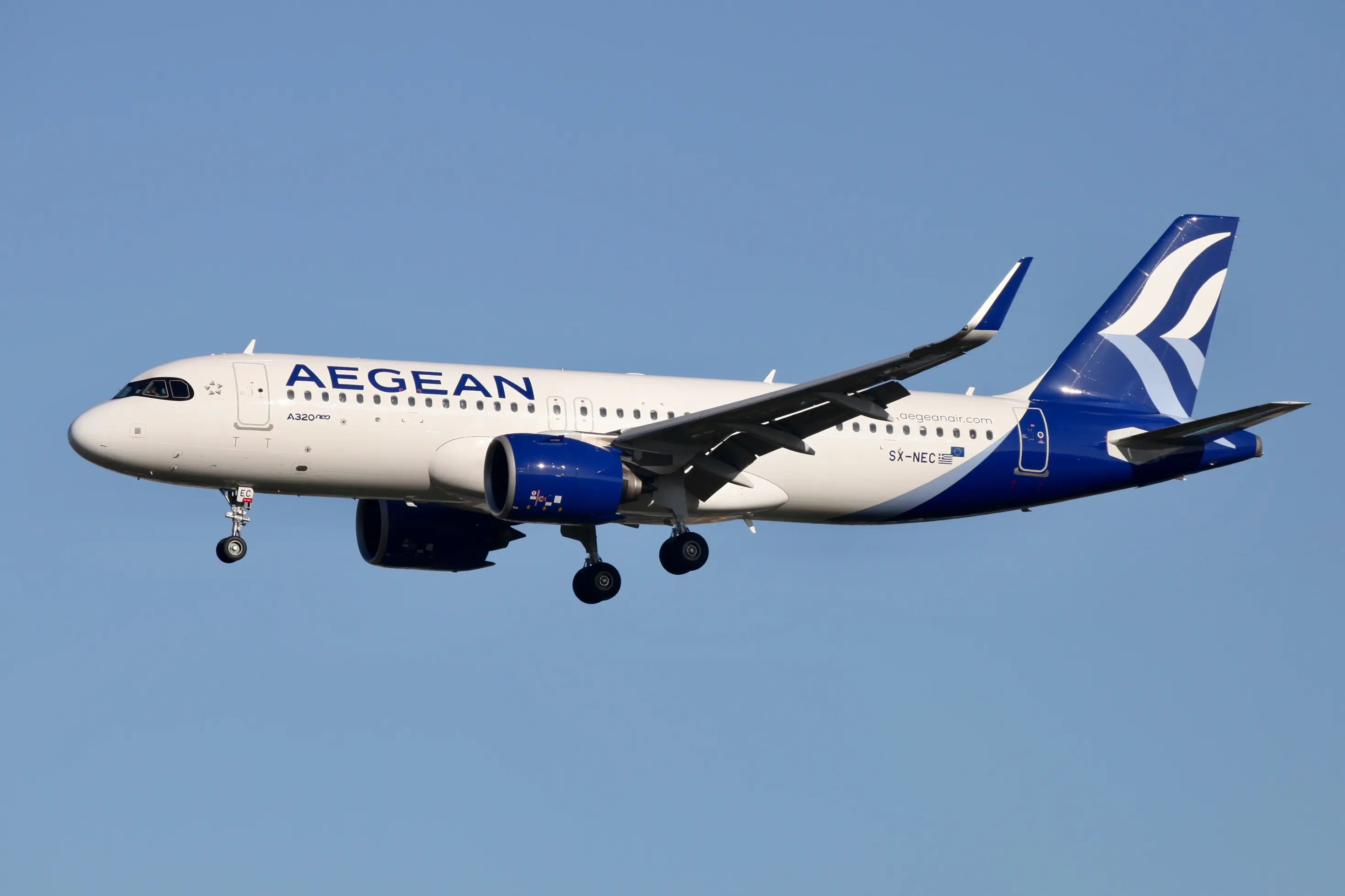 Aegean Airlines Airbus A320neo aircraft in flight, displaying the airline's logo and livery, against a clear blue sky.