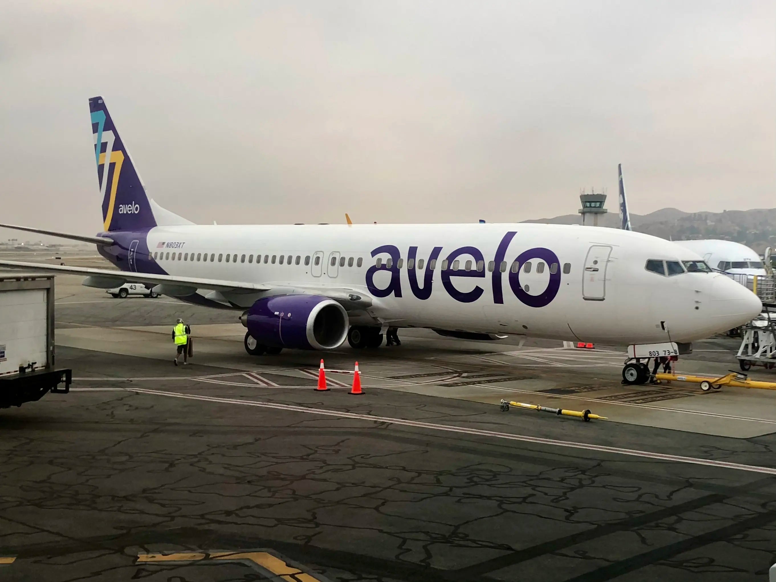Avelo Airlines Boeing 737-800 parked at Burbank Airport; plane's livery visible with ground crew and equipment nearby, photographed in May 2021.