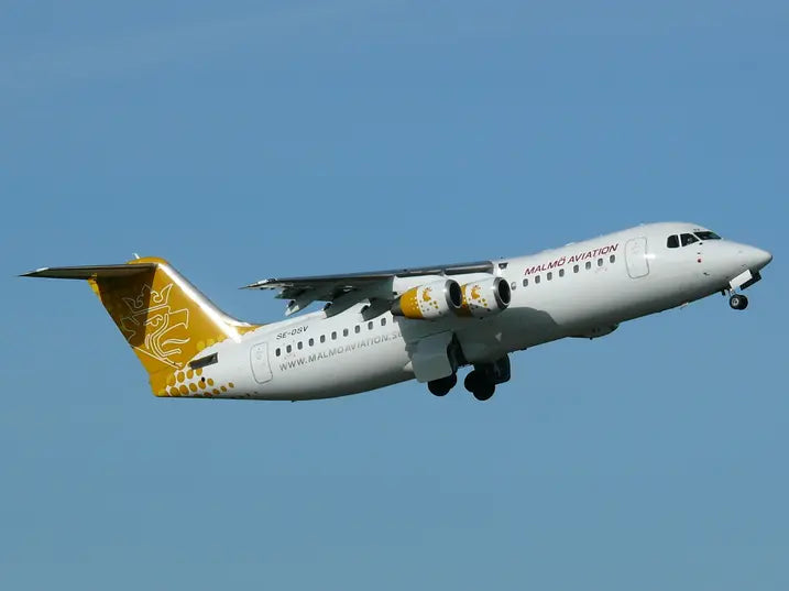 Malmö Aviation aircraft in flight with golden tail design, captured against a clear blue sky.