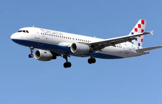 A Croatia Airlines Airbus A320 aircraft in flight against a clear blue sky, showing the airline's logo and checked tail design.