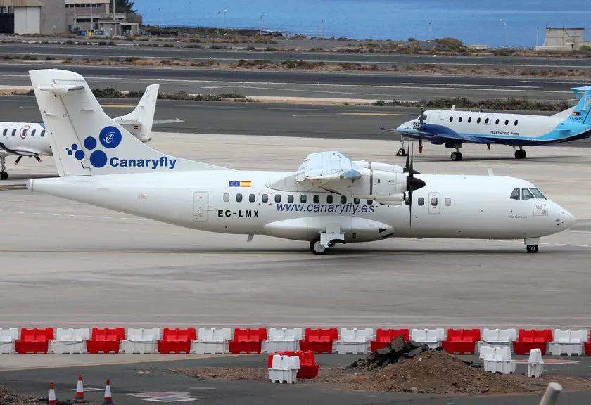 CanaryFly ATR 42-320 aircraft parked on the tarmac at Gran Canaria Airport with another plane visible in the background.
