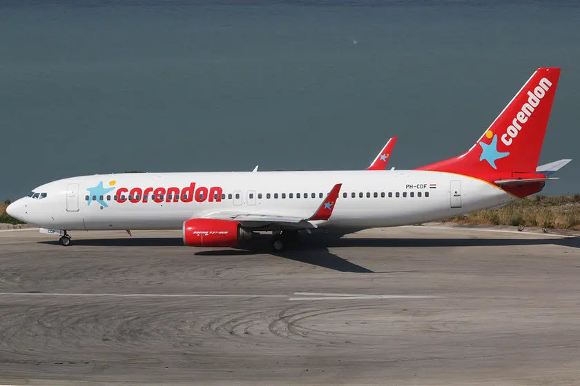 Corendon Airlines Boeing 737-8K2 on a runway with lake in background, displaying red and white livery with company logo on tail.