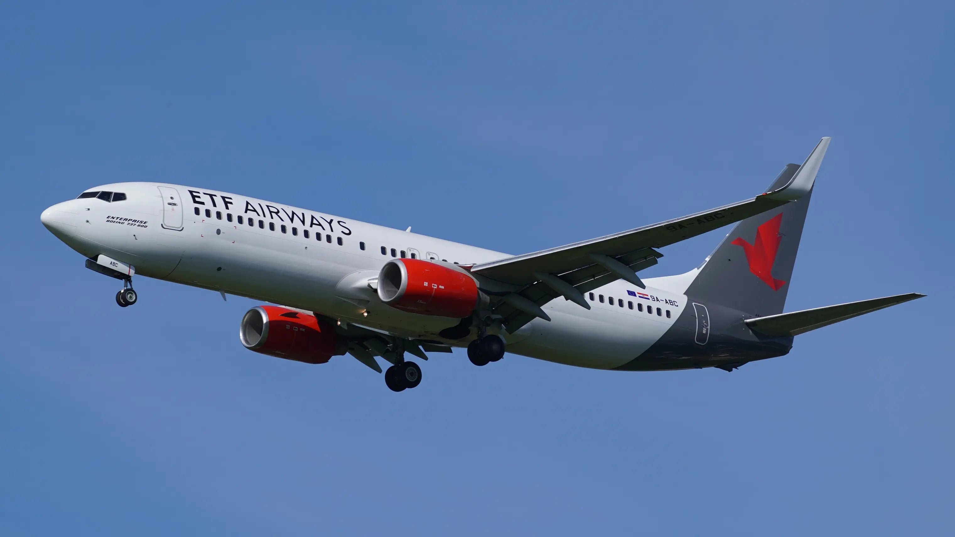 ETF Airways Boeing 737-8Q8(WL) aircraft with red engines in flight approaching Dresden Airport under a clear blue sky.