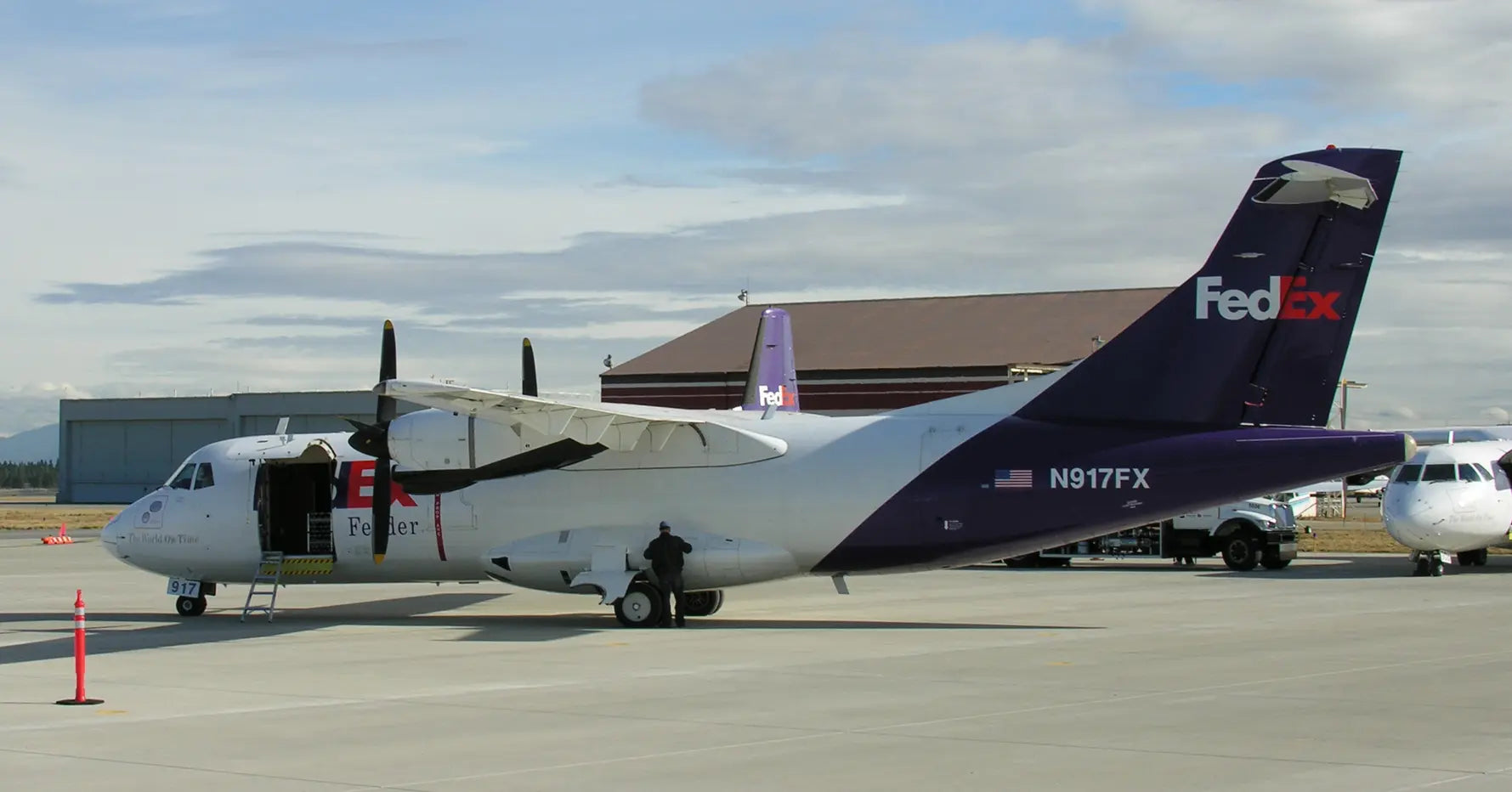 FedEx ATR 42 aircraft on a tarmac with tail number N917FX, cargo door open and parked at an airport with a building in the background.