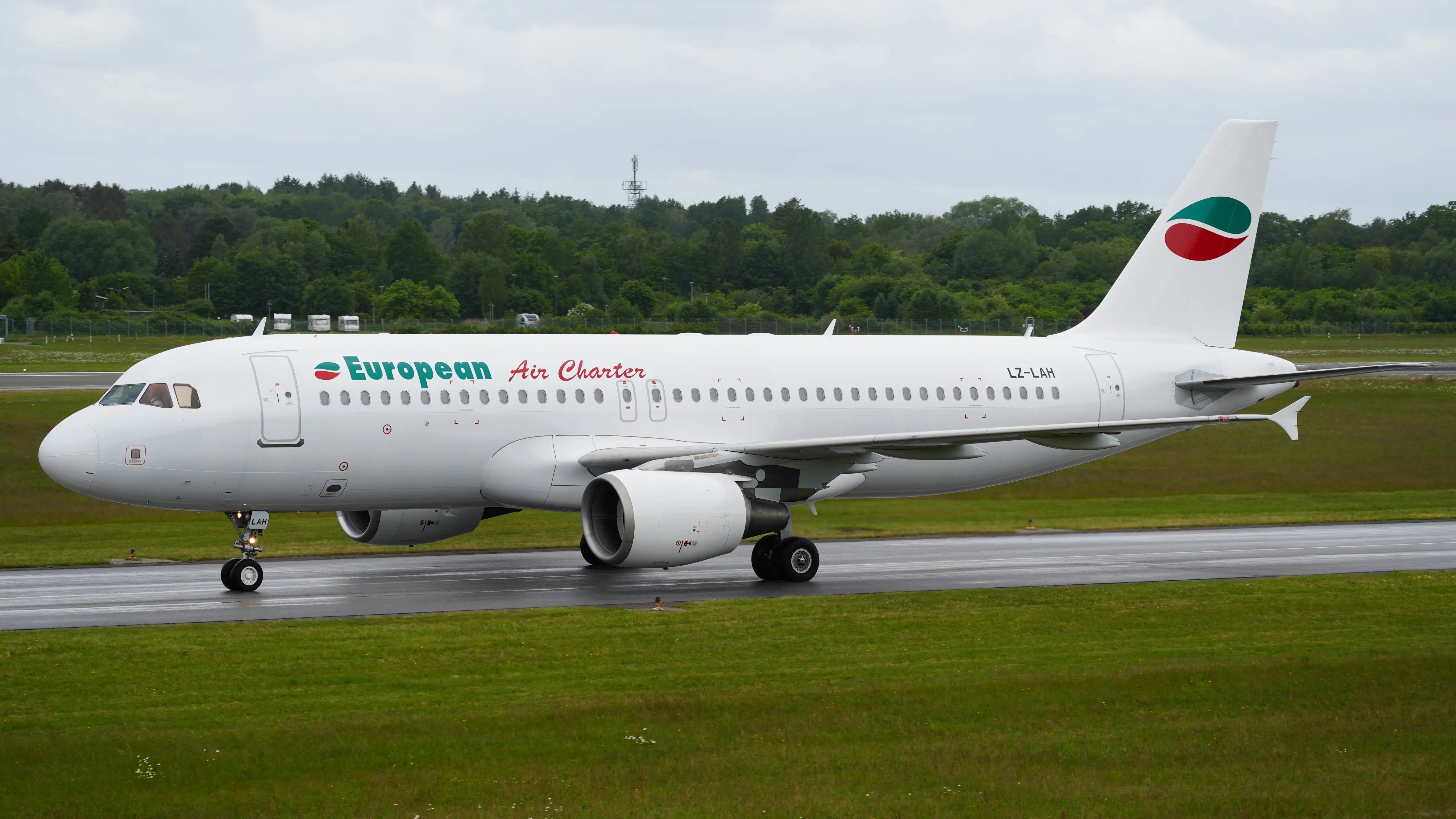 European Air Charter Airbus A320-214 LZ-LAH taxiing on a runway at Hamburg Airport, with a forested background and overcast sky.