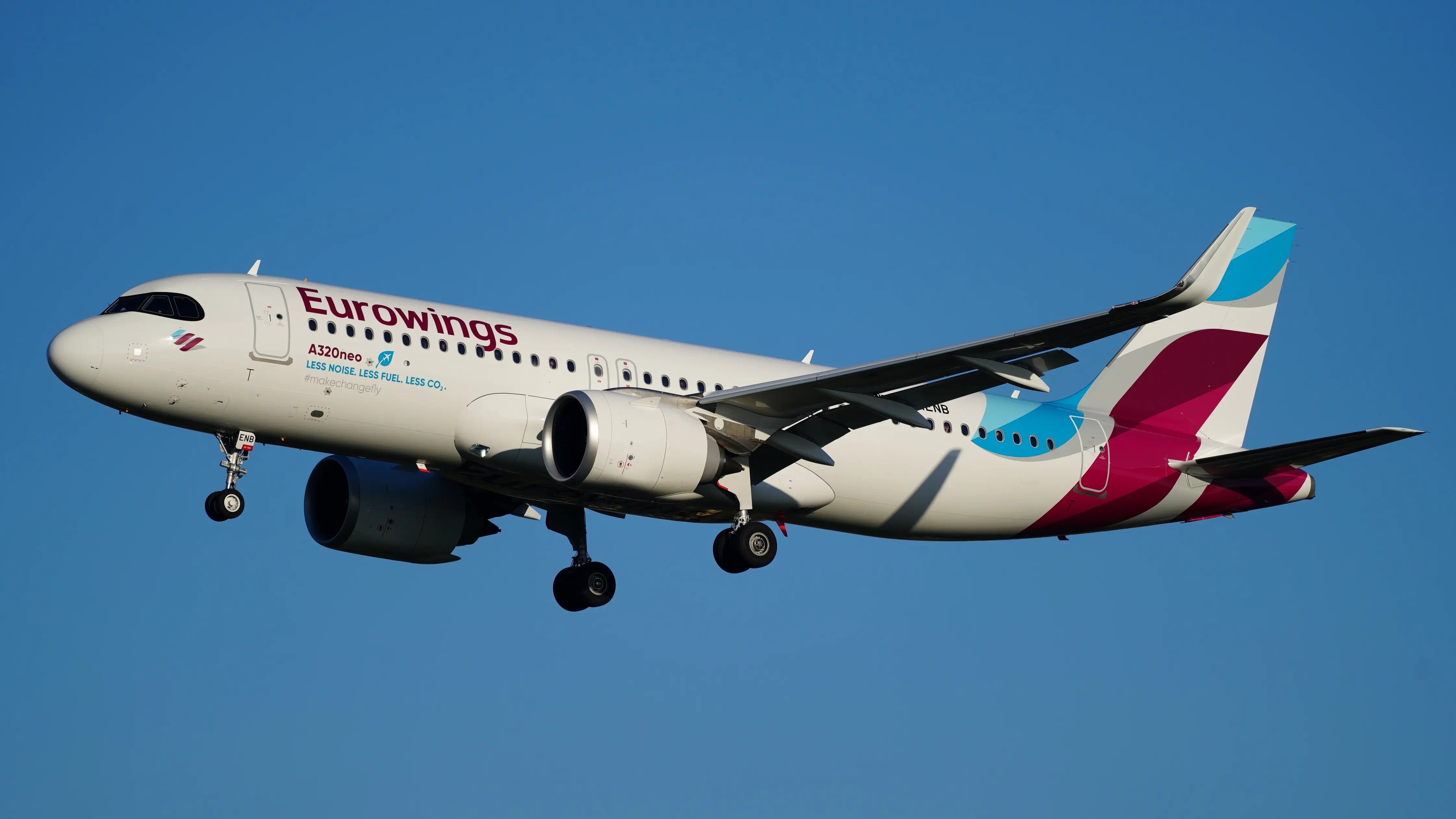 Eurowings Airbus A320-251N airplane in flight with landing gear extended, against a clear blue sky.
