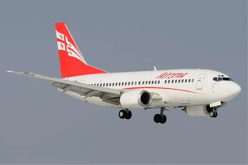 Airzena Boeing 737-500 aircraft in flight with red and white livery, featuring a red tail fin with the Georgian flag design on it.