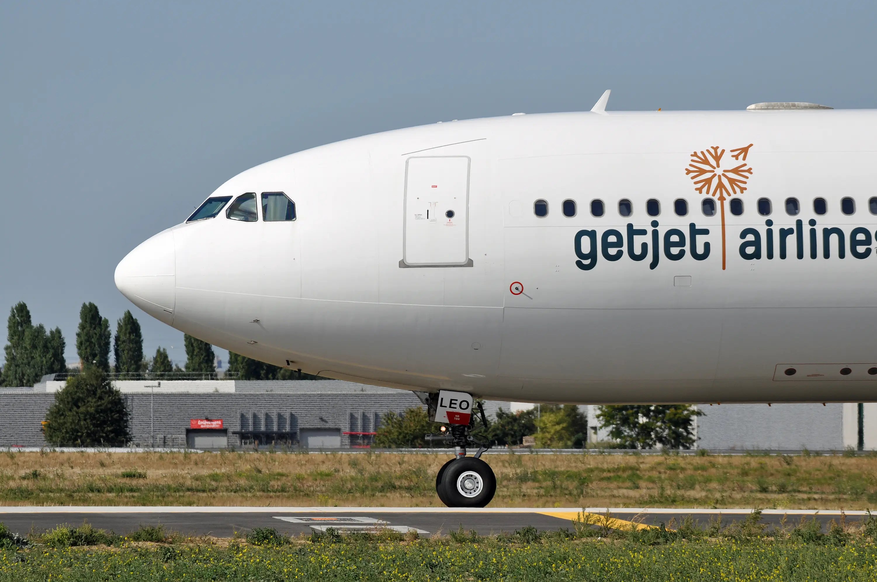 Close-up of a Getjet Airlines aircraft's front section on a runway, featuring its white fuselage and logo near the cockpit windows.