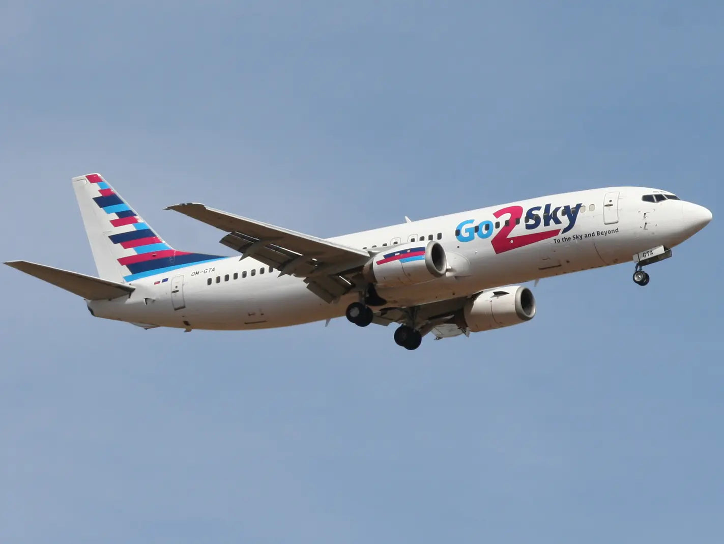 A white Go2Sky commercial airplane with red and blue tail in flight against a clear sky.