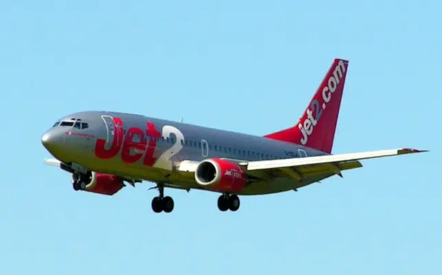 A Jet2 airplane approaching for landing against a clear blue sky with landing gear deployed.