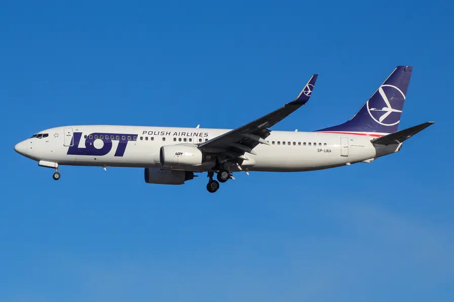 A LOT Polish Airlines Boeing 737 aircraft in flight against a clear blue sky.