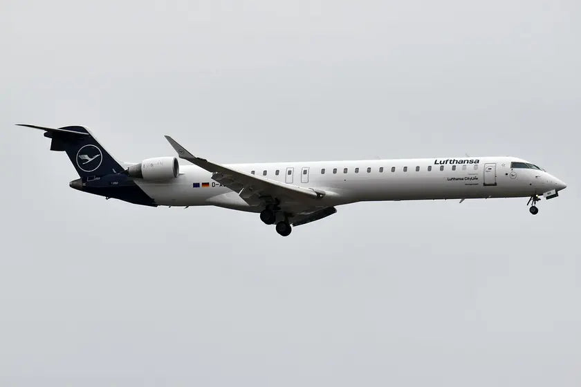 Lufthansa CityLine Bombardier CRJ-900LR aircraft in flight, side view against a gray sky.