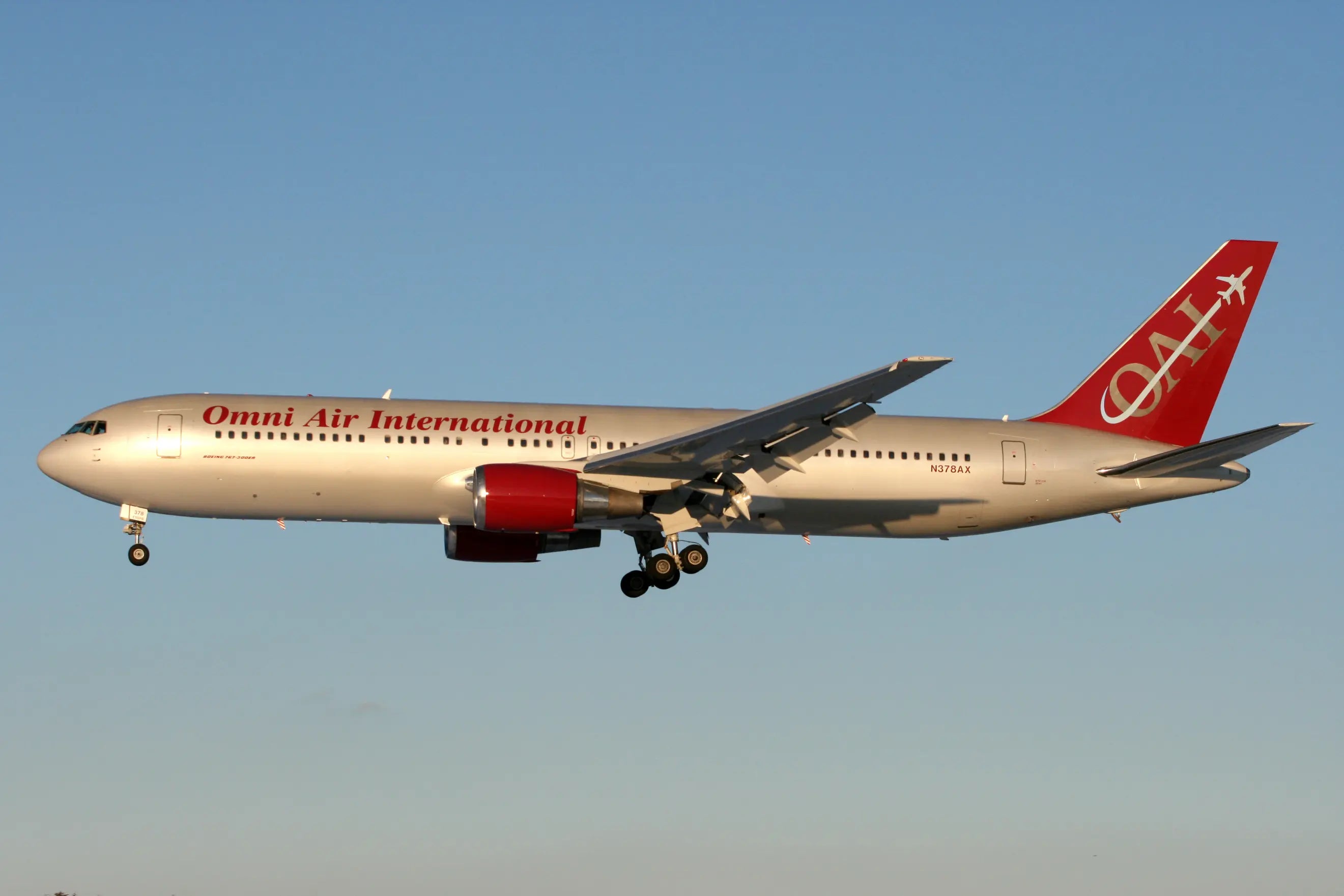 Omni Air International Boeing 767 aircraft in flight with a clear blue sky background.