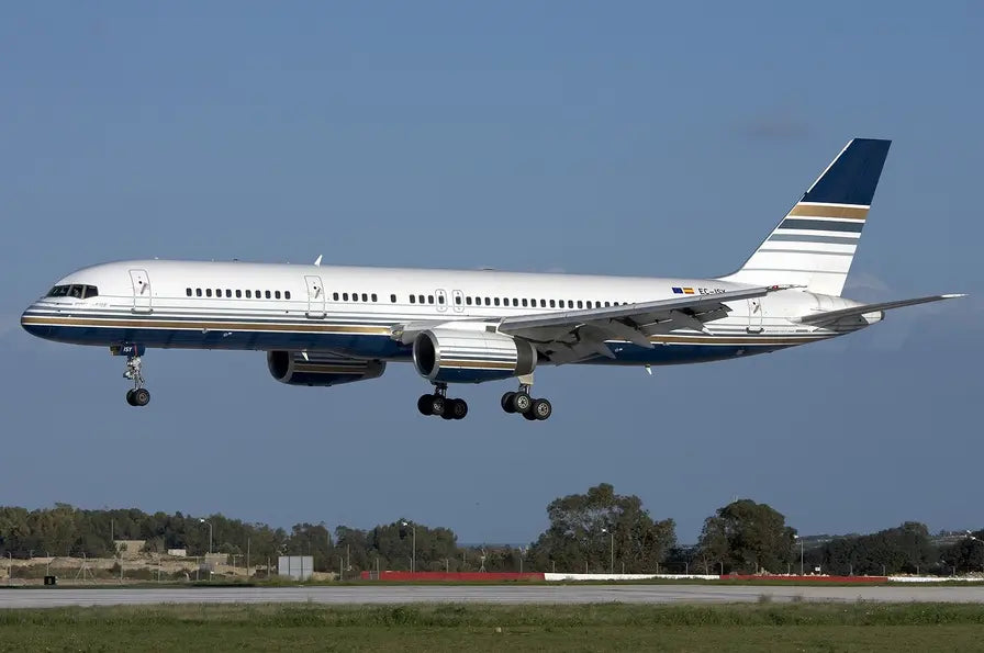 Privilege Style Boeing 757-256 airplane landing with landing gear extended against a clear blue sky.