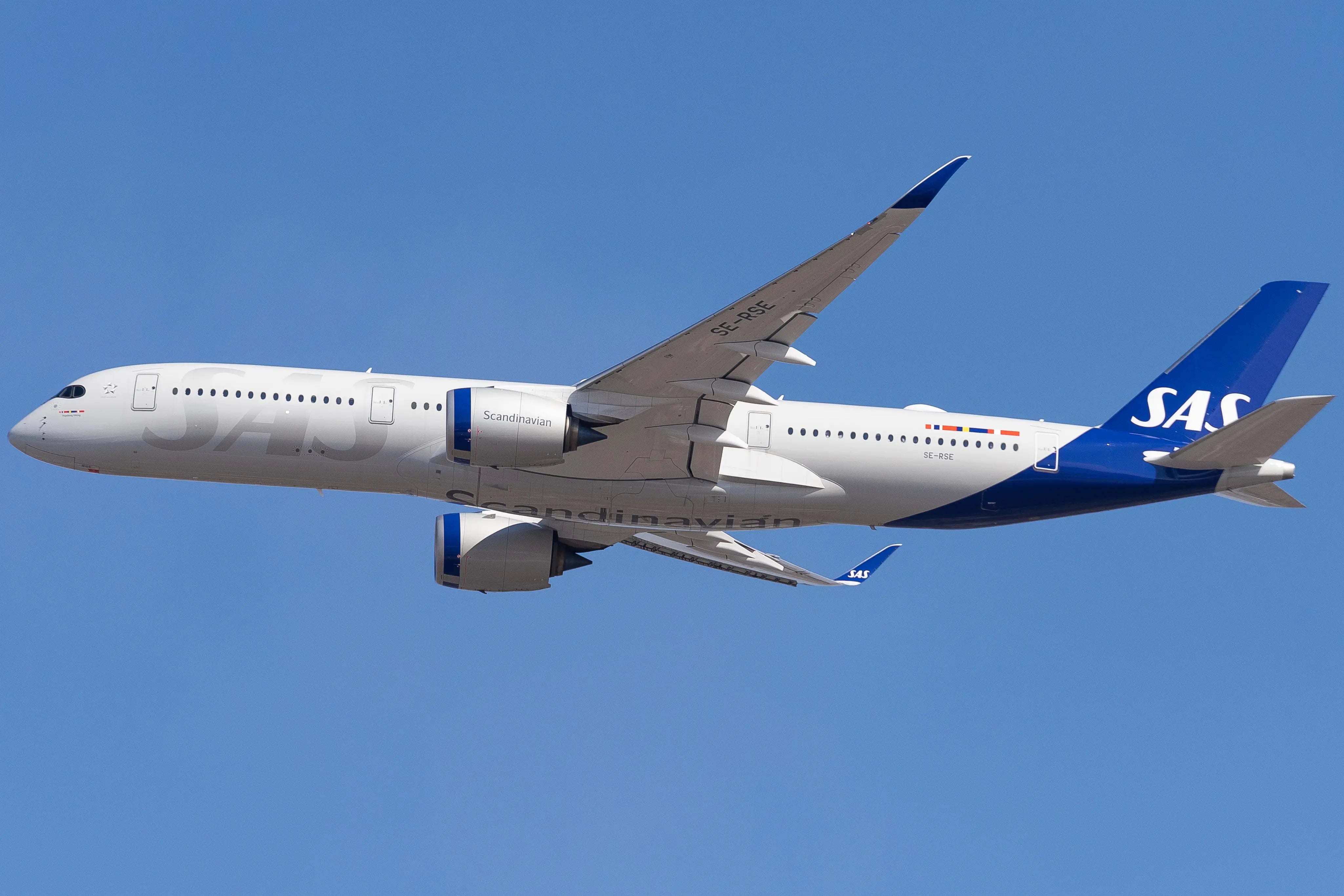 A Scandinavian Airlines Airbus A350-900 aircraft, registration SE-RSE, flying against a clear blue sky, seen from the left side in flight.