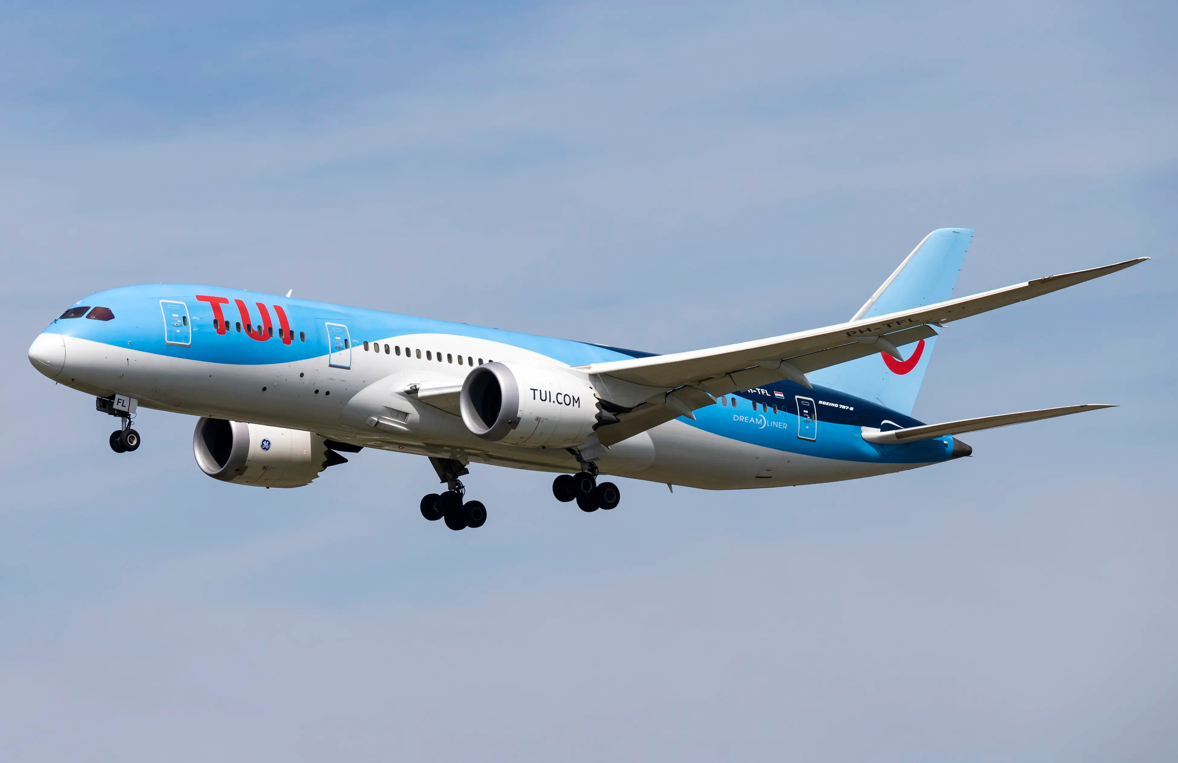 A TUI Airlines Netherlands Boeing 787-8 Dreamliner in flight, displaying its blue livery against a clear sky, with landing gear deployed.