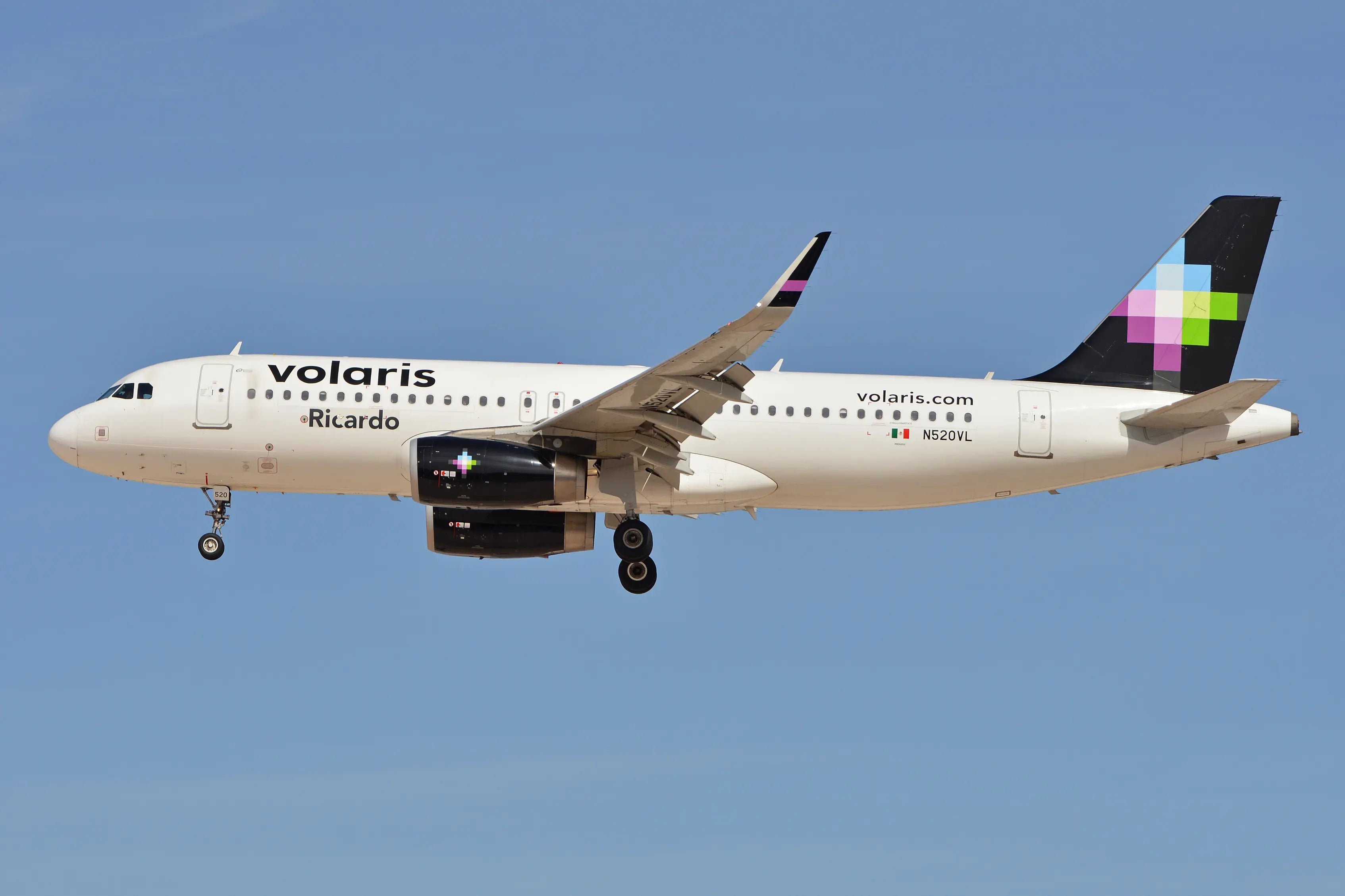 Volaris Airbus A320-232 with registration N520VL in flight, featuring the airline's livery and logo, against a clear blue sky.