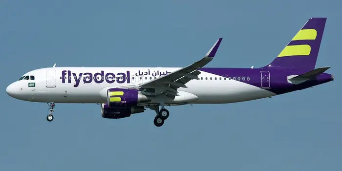 A Flyadeal aircraft in flight, painted in purple and white with green accents, displaying the Flyadeal logo on the fuselage.