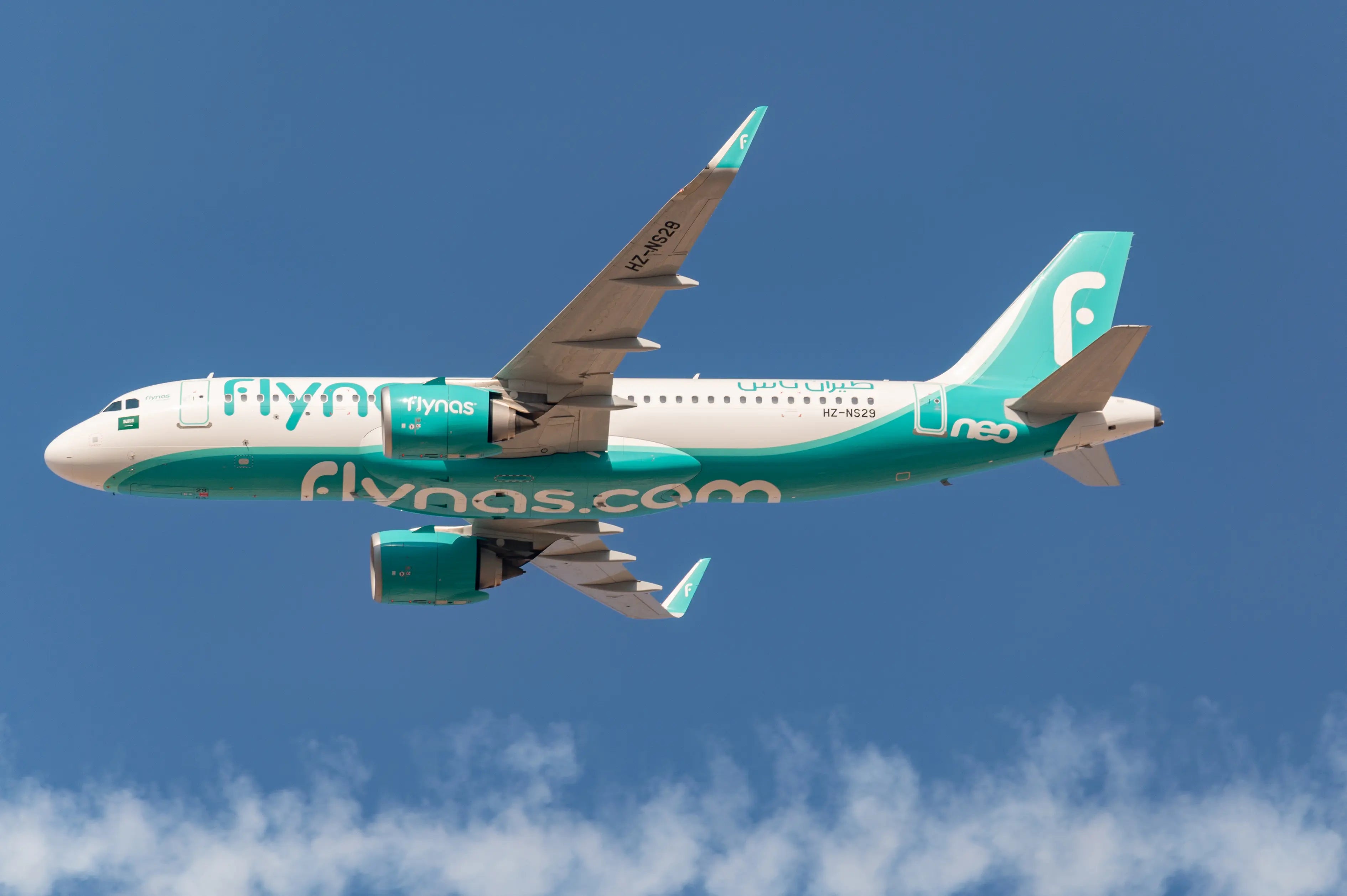 Flynas Airbus A320neo aircraft in flight against a clear blue sky.
